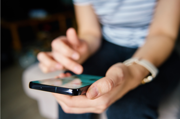 Person holding a smartphone and scrolling through social media, representing the idea of creating content that converts into leads or sales.